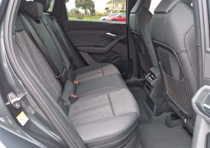 Vue intérieure côté gauche montrant la banquette arrière en tissu et cuir de l'Audi Q6 e-tron Performance S-Line gris Manhattan.