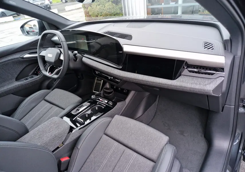 Intérieur côté conducteur de l'Audi Q6 e-tron Performance S-Line 2025 avec tableau de bord numérique et finition tissu gris.