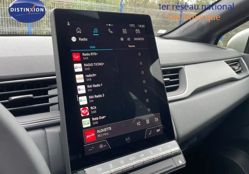 Écran tactile central allumé du tableau de bord du Renault Captur gris Rafale, affichant les stations radio numériques.