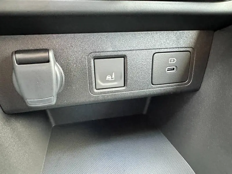 Détail intérieur montrant une prise USB-C, un bouton d'assistance au stationnement et une prise 12V sur Dacia Sandero Stepway 2025.