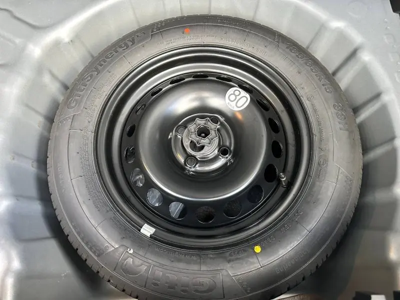 Gros plan sur la roue de secours noire du Dacia Sandero Stepway Extreme 2025, montée dans le coffre gris.