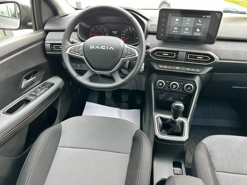 Intérieur du DACIA Sandero 2025 vu de face, avec volant multifonction, écran tactile et boîte manuelle noire.