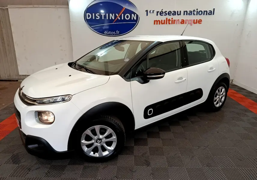 Citroën C3 blanche vue 3/4 avant droit, avec protections latérales noires et jantes alliage argentées.