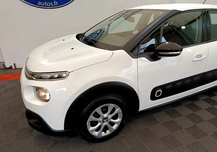 Vue 3/4 avant gauche d'une Citroën C3 blanche avec protections latérales noires et jantes alliage.