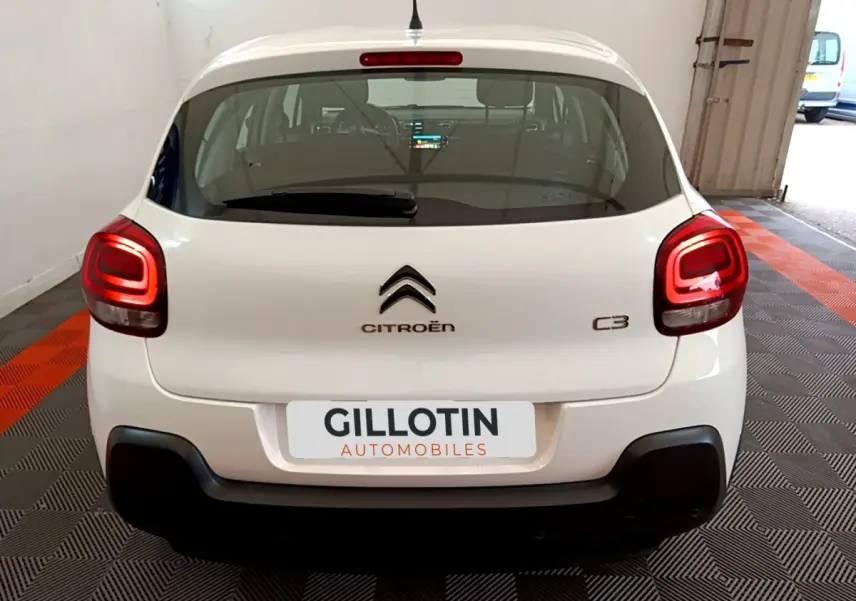 Vue arrière d'une Citroën C3 blanche de 2019 avec feux arrière allumés dans un garage.