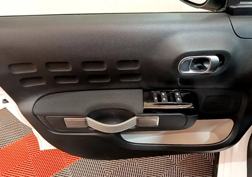 Gros plan sur la porte avant gauche blanche d'une Citroën C3 2019 avec commandes de vitres et poignée noire.