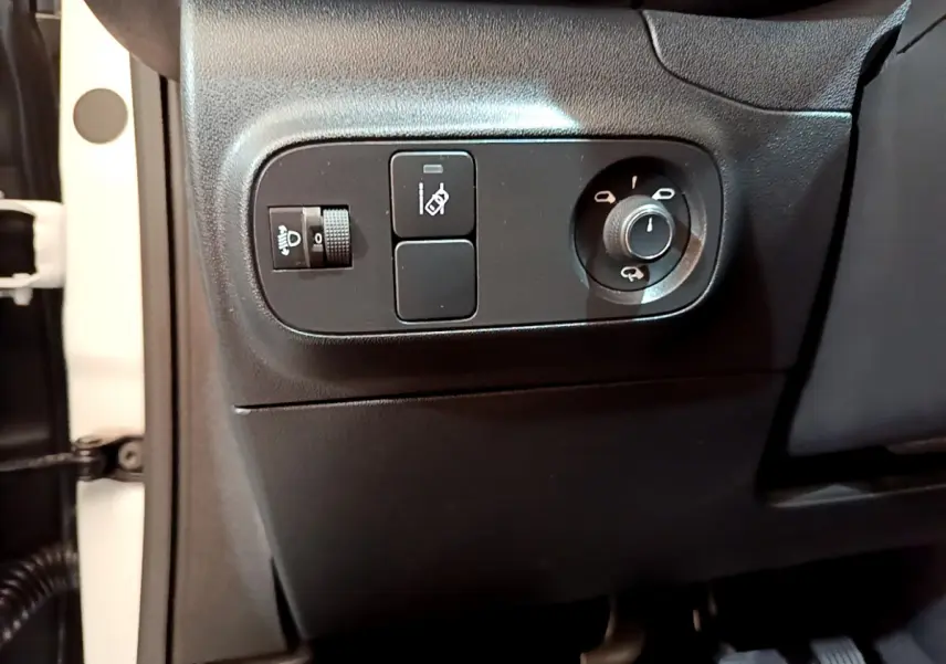 Vue rapprochée des commandes de réglage des phares et rétroviseurs côté conducteur d'une Citroën C3 blanche de 2019.