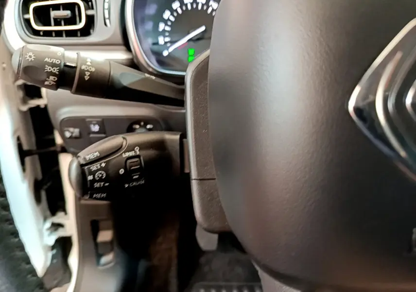 Gros plan sur le volant cuir et commandes au volant côté gauche d'une Citroën C3 blanche de 2019.