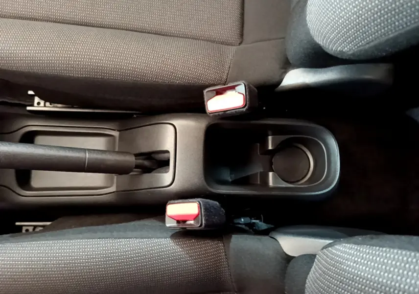 Vue plongeante sur la console centrale noire entre les sièges avant gris foncé de la Citroën C3 blanche de 2019.
