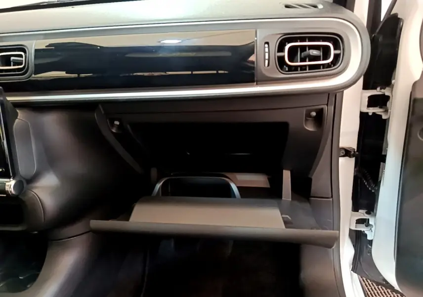 Intérieur de la Citroën C3 2019, vue côté passager sur la boîte à gants ouverte et la planche de bord noire brillante.