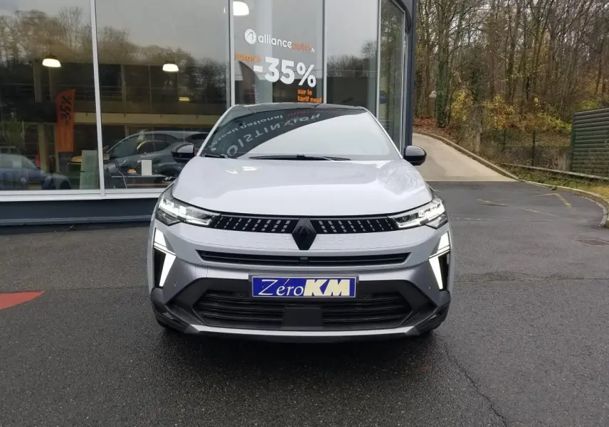 Vue frontale d'un Renault Captur gris Rafale 2025 avec éclairage LED distinctif et plaque "Zéro KM" visible.