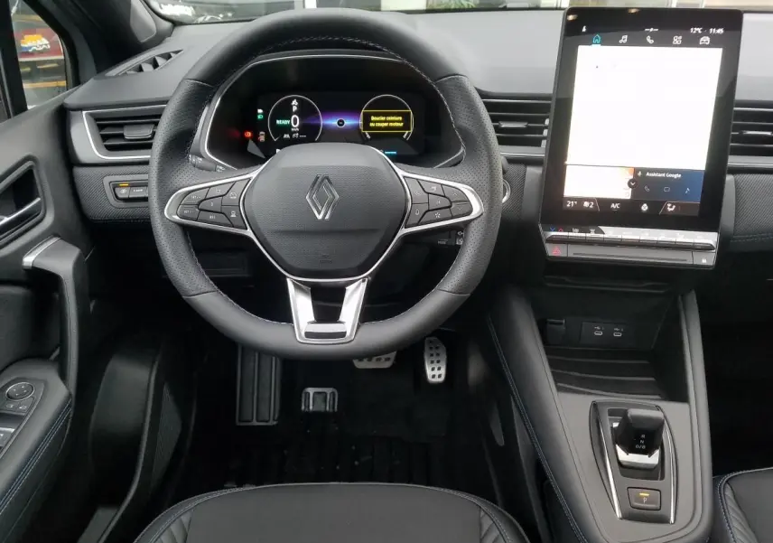Vue intérieure du tableau de bord du Renault Captur gris Rafale 2025, avec volant multifonction et écran tactile vertical.