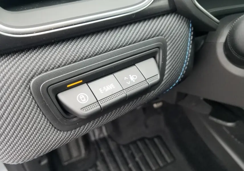 Gros plan sur les boutons de commande E-SAVE et réglage des phares sur la console côté conducteur du Renault Captur gris Rafale.