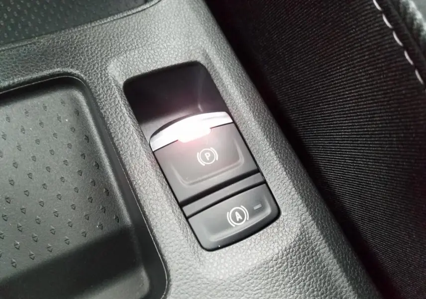 Gros plan sur les boutons du frein de parking électrique et de la fonction Auto-Hold dans la console centrale du Renault Captur gris Rafale.