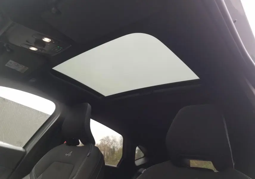 Intérieur du Renault Captur gris Rafale 2025 vu de l'arrière, avec toit ouvrant panoramique et sièges noirs Alpine.