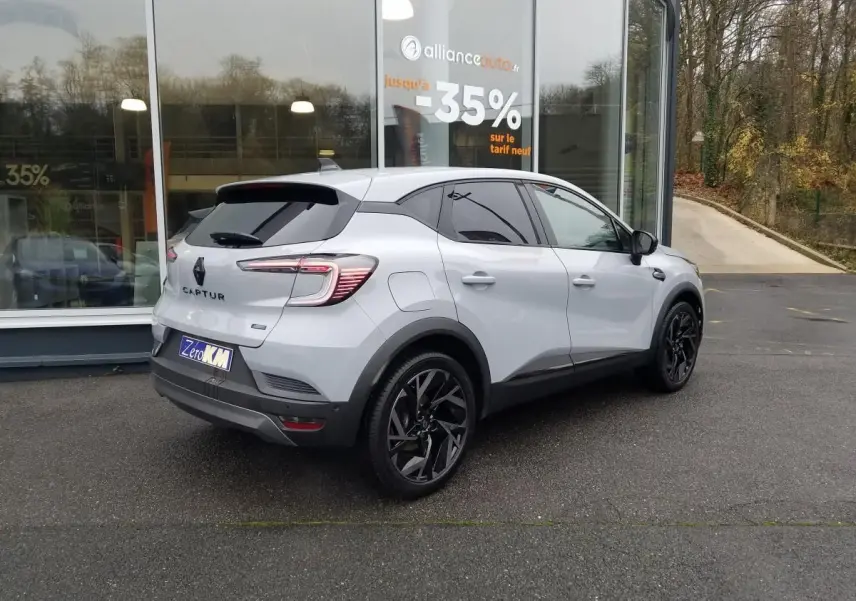 Renault Captur gris Rafale en 3/4 arrière droit, toit ouvrant noir brillant et jantes 19 pouces noires.