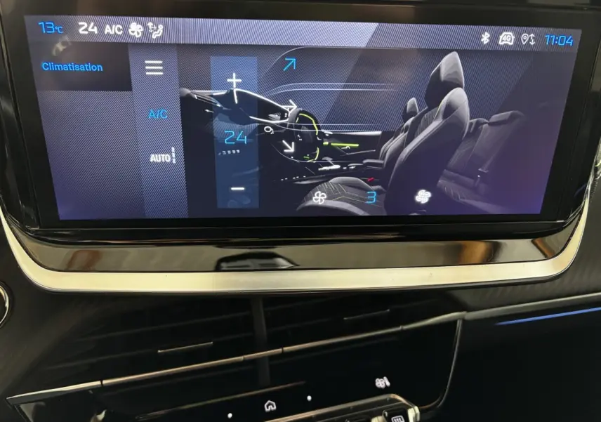 Écran tactile central de la Peugeot 208 Hybrid gris clair montrant la commande de climatisation et l'intérieur du véhicule.