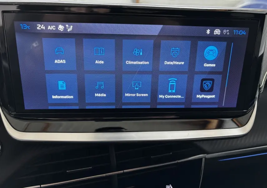 Écran tactile central affichant les options multimédia et climatisation dans l’habitacle d’une Peugeot 208 Hybrid 110 e-DCS6 GT gris clair.
