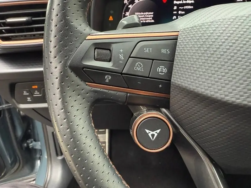 Gros plan sur le volant cuir perforé noir du CUPRA Formentor 2025, avec commandes multifonctions et molette cuivre.