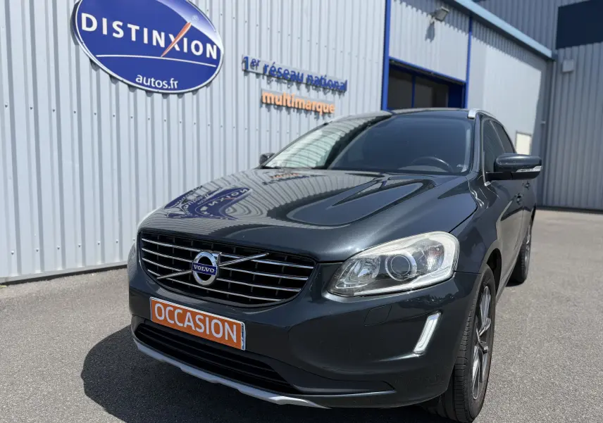 Volvo XC60 gris foncé en 3/4 avant droit, avec calandre distinctive et plaque orange "OCCASION" visible.