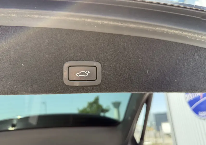 Gros plan sur le bouton d'ouverture électrique du coffre, intérieur du hayon d'un Volvo XC60 gris foncé 2016.