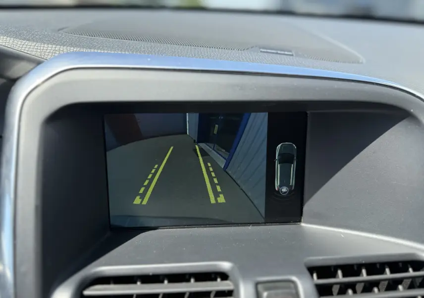 Écran de caméra de recul du Volvo XC60 gris foncé 2016, affichant les lignes de guidage jaunes et vue 360° du véhicule.