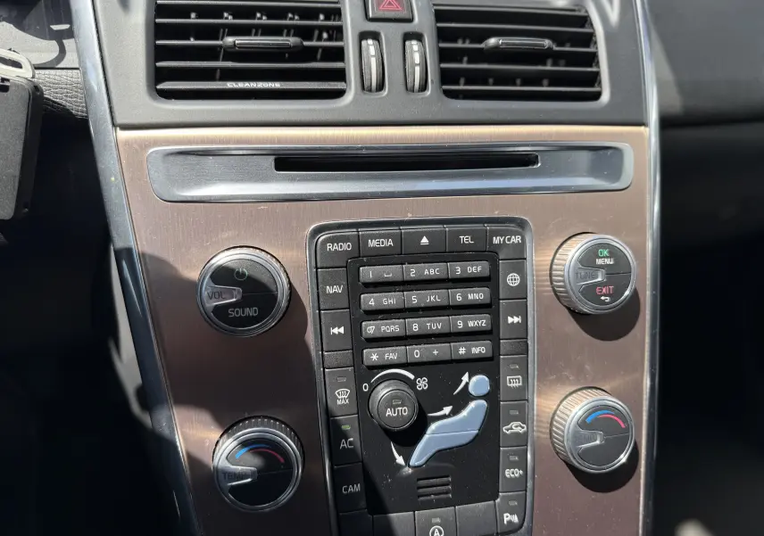 Vue rapprochée de la console centrale du Volvo XC60 gris foncé, montrant les commandes audio et climatisation.