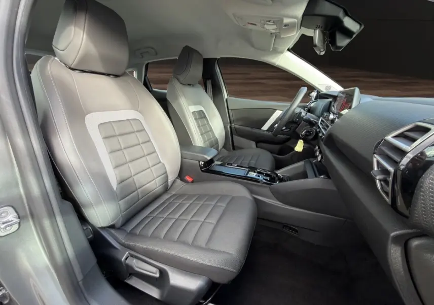 Vue intérieure côté conducteur de la Citroën C4 hybride 2025, sièges gris et tableau de bord moderne avec écran tactile.