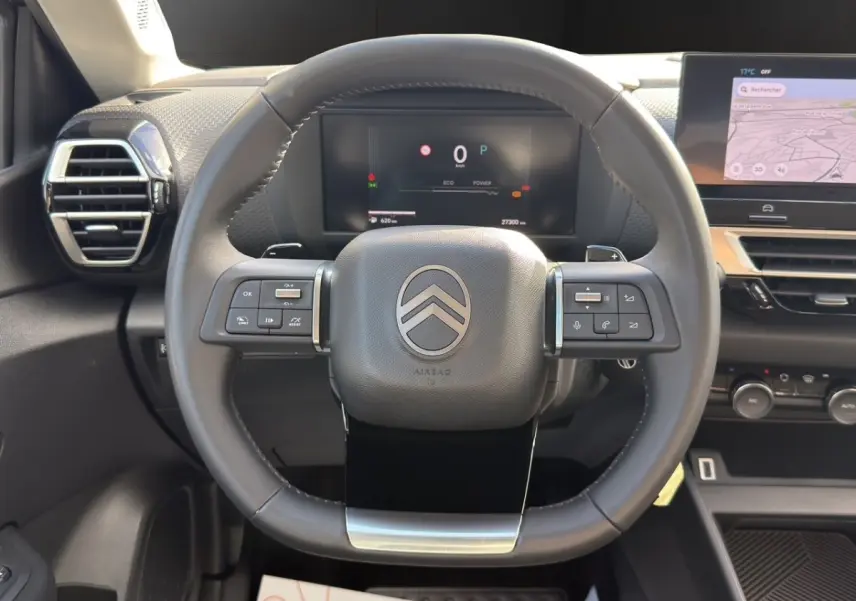 Vue centrée sur le volant cuir multifonctions et le tableau de bord numérique de la Citroën C4 hybride 2025.