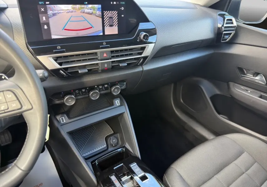 Vue intérieure côté passager de la Citroën C4 hybride 2025, tableau de bord avec écran tactile et console centrale noire.