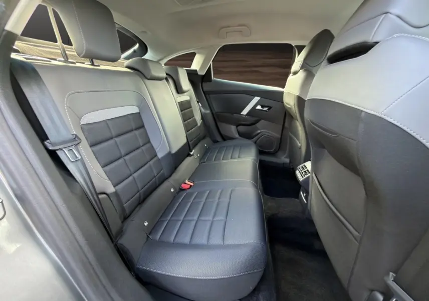 Vue intérieure arrière côté droit de la banquette noire et grise de la Citroën C4 hybride 2025 avec ceintures et appuie-têtes.