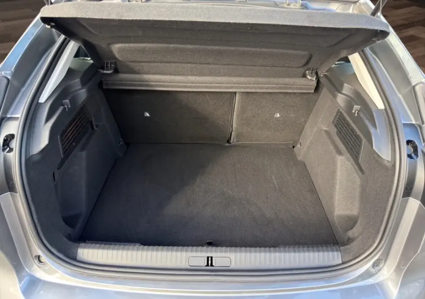 Coffre ouvert vu de l'arrière d'une Citroën C4 hybride gris foncé, montrant un espace de chargement propre et spacieux.