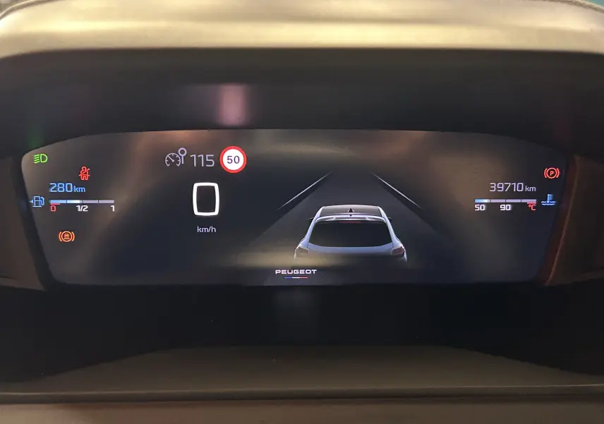 Tableau de bord numérique du Peugeot 208 gris Selenium, affichant vitesse, autonomie et alertes de conduite.
