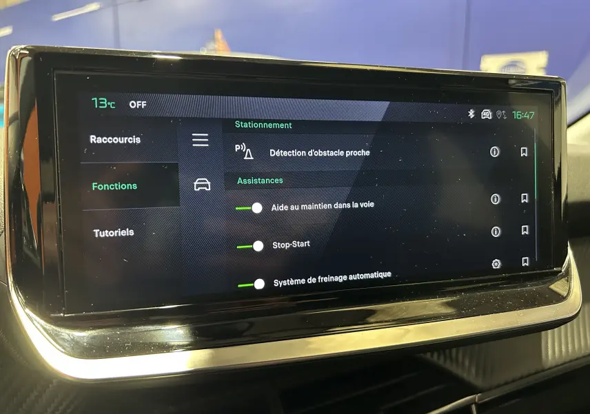 Écran tactile intérieur de la Peugeot 208 gris Selenium affichant les assistances à la conduite et la température à 73°C.