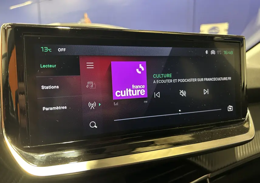 Écran tactile central du Peugeot 208 gris Selenium, affichant la radio France Culture en intérieur.