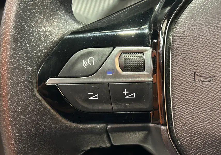 Gros plan sur les commandes de volume vocal sur le volant d’une Peugeot 208 gris Selenium, version 2025.
