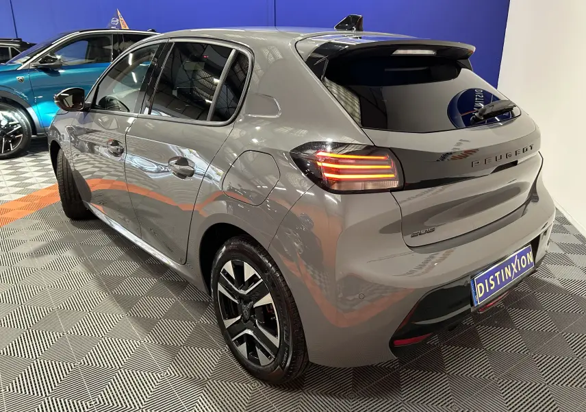 Peugeot 208 gris Selenium vue 3/4 arrière droit, feux arrière allumés et jantes noires distinctives.
