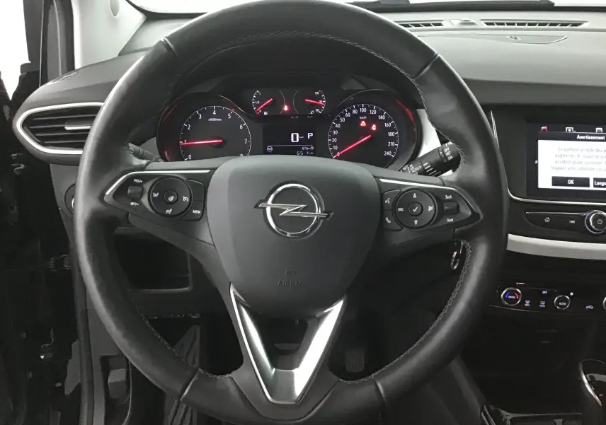Vue intérieure centrée sur le volant noir de l'Opel Crossland 2022 avec tableau de bord et écran tactile visibles.