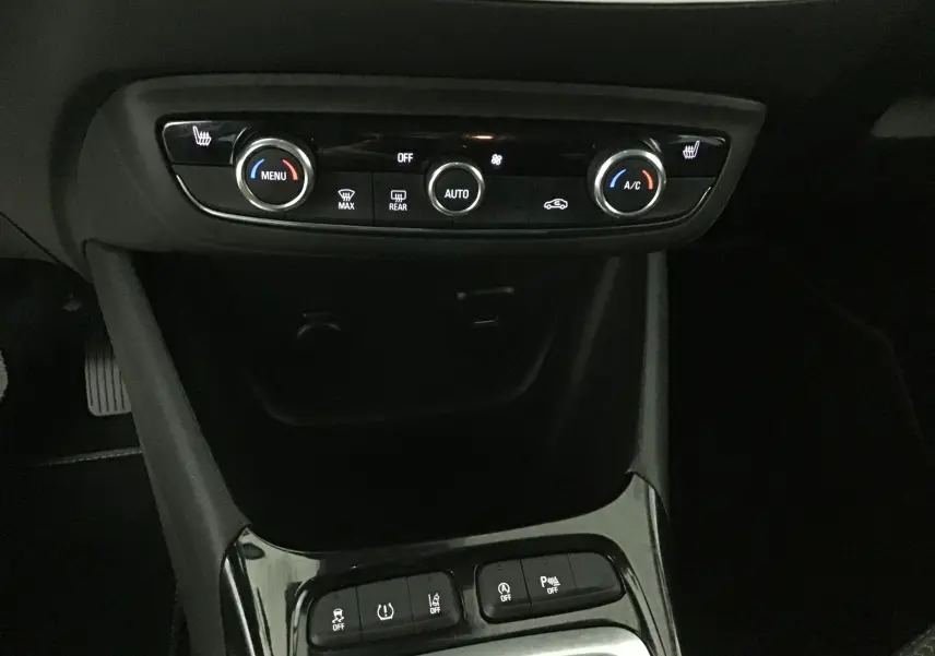 Gros plan sur la console centrale de l'Opel Crossland noire 2022, montrant les commandes de climatisation et les boutons d'assistance.