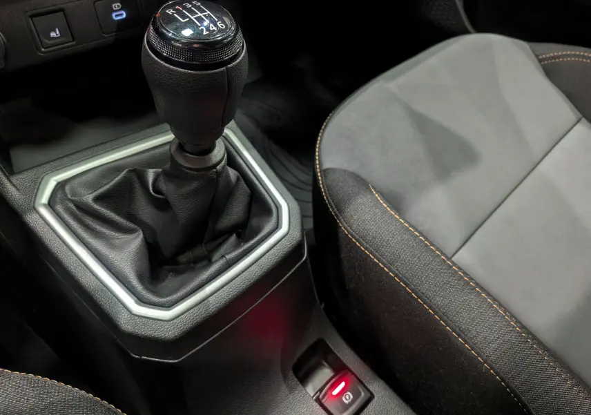 Le levier de vitesses manuel de la Dacia Sandero Stepway TCe 110 blanc glacier avec siège tissu noir et coutures orange.