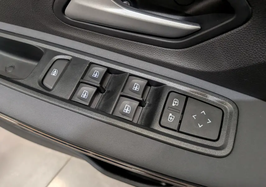 Gros plan sur les commandes de lève-vitres et réglage des rétroviseurs côté conducteur d'une Dacia Sandero Stepway TCe 110 Blanc Glacier.