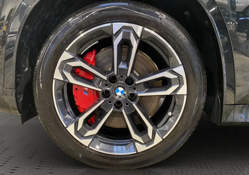 Gros plan sur la jante avant droite du BMW X1 noir Saphir, avec étrier de frein rouge M Sport visible.