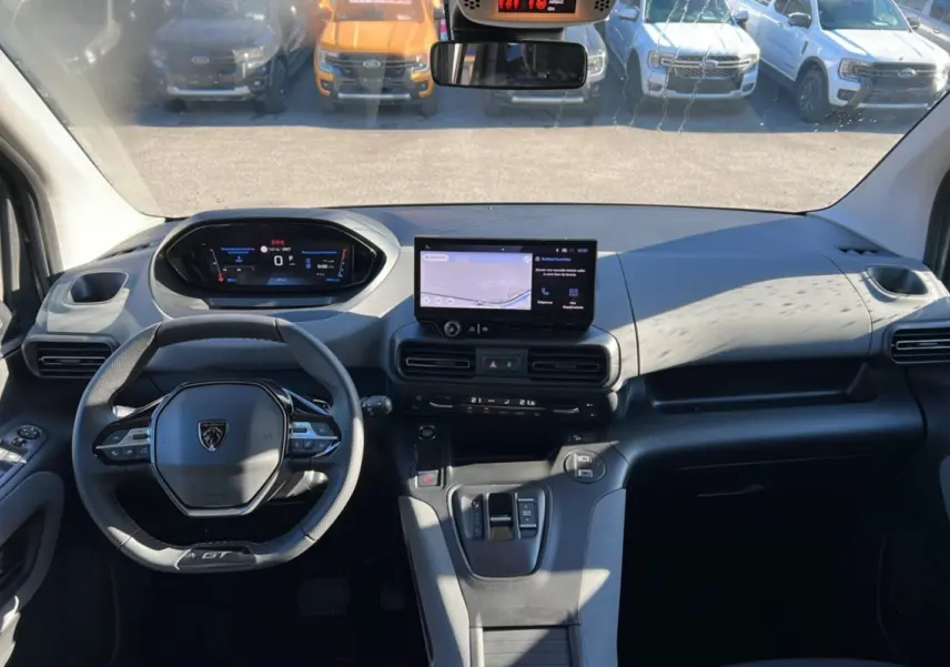 Vue intérieure avant du Peugeot Rifter 2025 GT Plus, tableau de bord moderne avec écran tactile et volant cuir multifonctions.