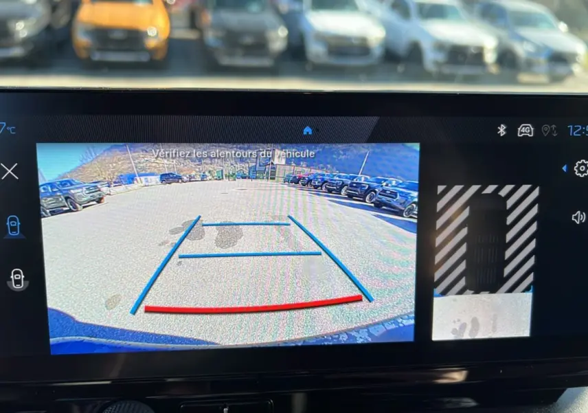 Écran de caméra de recul du Peugeot Rifter vert Sirkka, vue arrière avec lignes de guidage et parking visible.