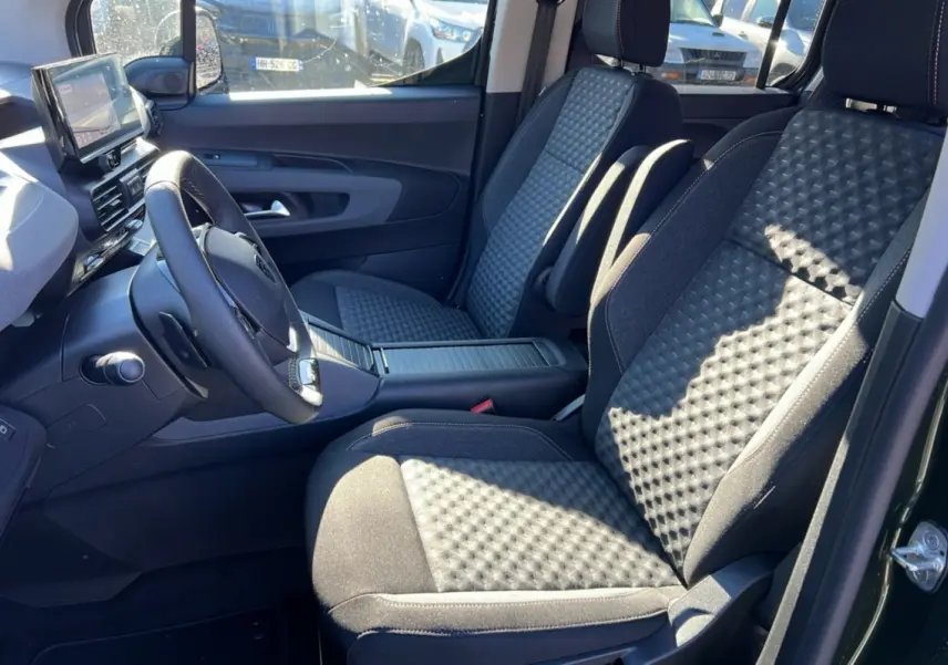 Vue intérieure côté conducteur du Peugeot Rifter 2025 vert sirkka, mettant en valeur les sièges tissu et le volant cuir multifonctions.