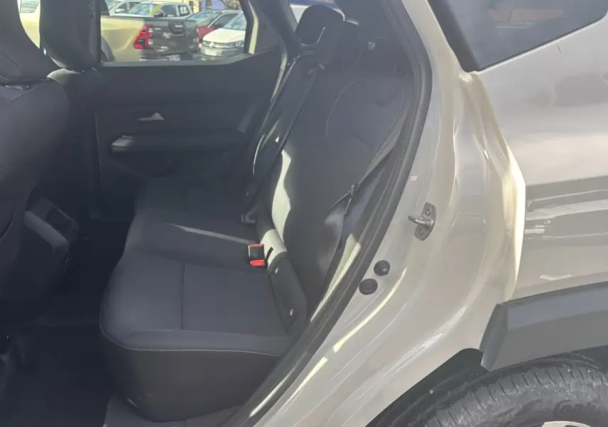 Vue intérieure côté arrière droit du Dacia Duster 2025 TCE 130 4x2 Journey couleur Sandstone, sièges noirs et banquette 60/40.