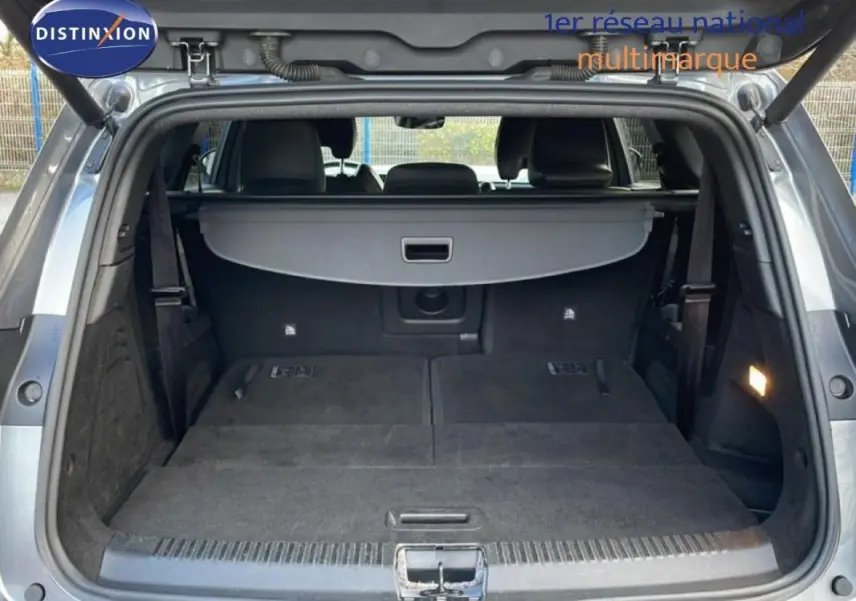 Coffre ouvert d’un Renault Espace gris 2024, vue arrière montrant l’espace de chargement avec banquette rabattue et cache bagages.