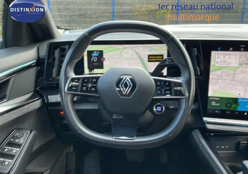 Vue intérieure centrée sur le volant cuir multifonctions et l’écran tactile du Renault Espace gris 2024 hybride.
