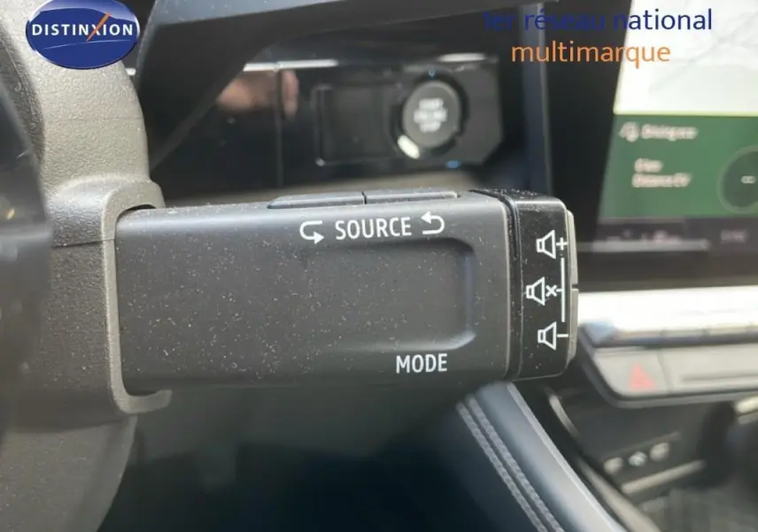 Gros plan sur la commande au volant du Renault Espace gris 2024, avec écran tactile et affichage numérique en arrière-plan.