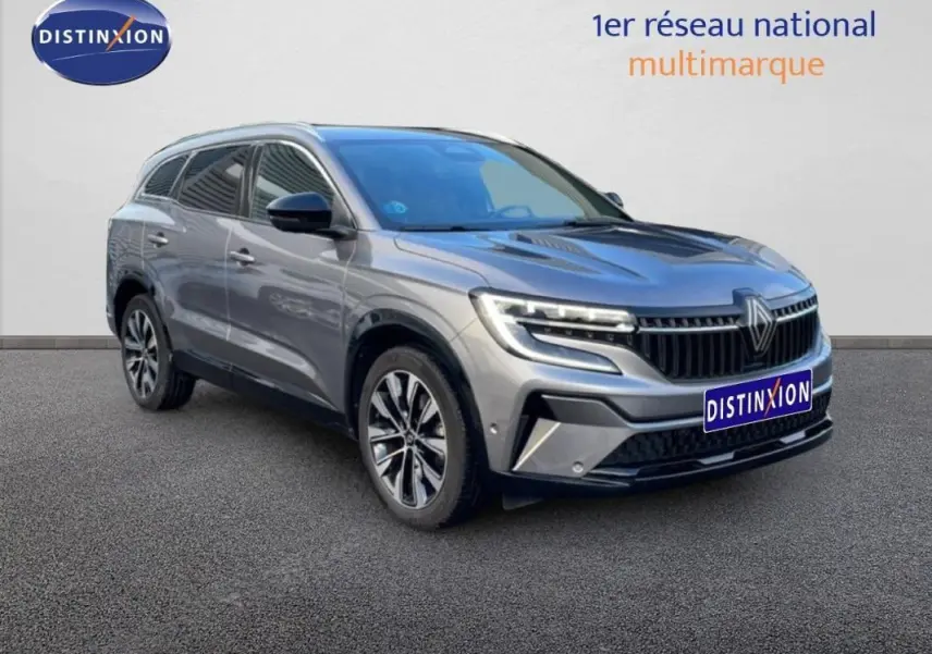 Renault Espace gris 2024 en 3/4 avant droit, avec barres de toit et jantes aluminium distinctives.